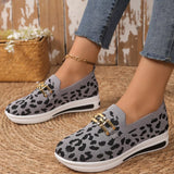 Gray leopard print shoes with gold accents worn by a person on a woven surface.