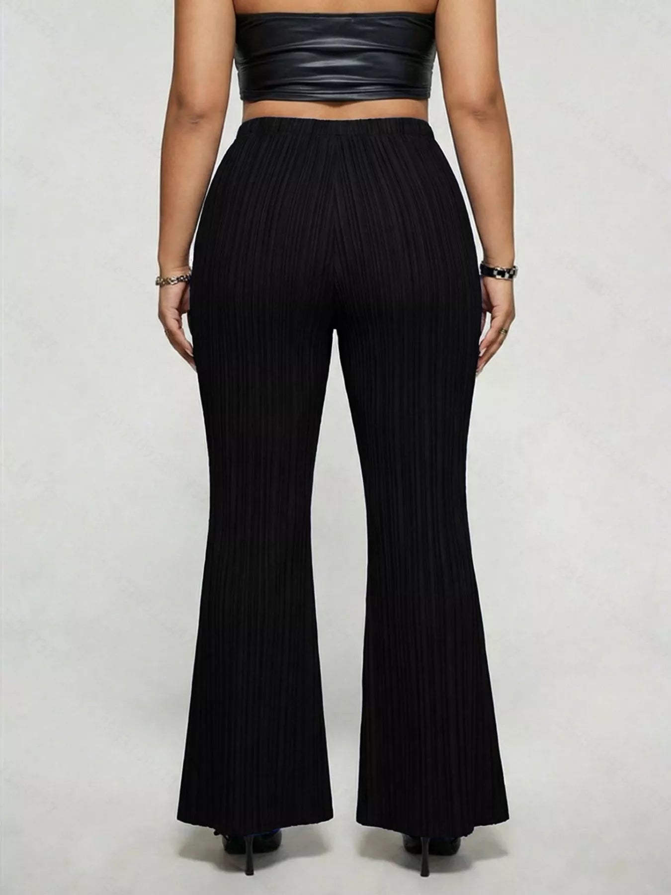 Model wearing black plus-size high-waisted flare pants styled with pointed-toe heels for an elegant and sophisticated look.