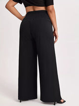 Model wearing black plus-size high-waisted wide-leg pants with a smocked waistband and side pockets.