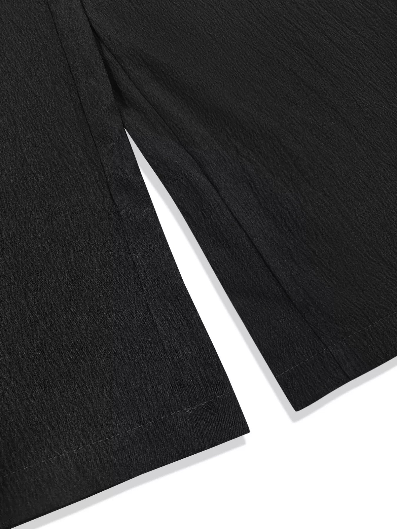 Model wearing black plus-size high-waisted wide-leg pants with a smocked waistband and side pockets.