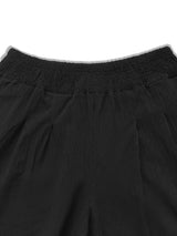 Model wearing black plus-size high-waisted wide-leg pants with a smocked waistband and side pockets.