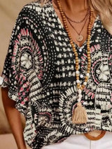 Black printed V-neck top with half sleeves and a relaxed boho-inspired fit paired with white shorts.