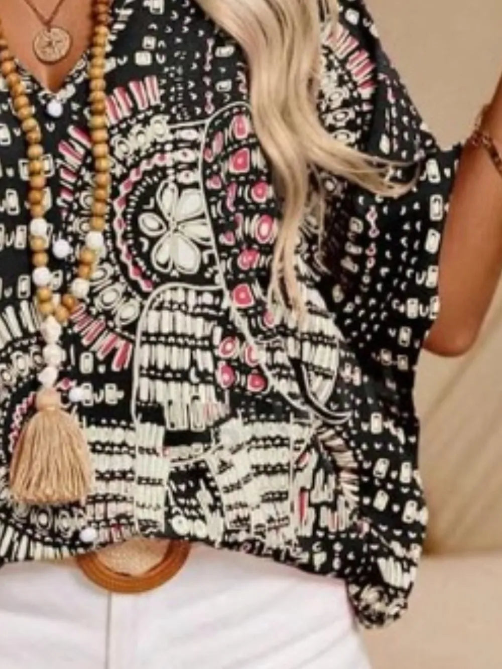 Black printed V-neck top with half sleeves and a relaxed boho-inspired fit paired with white shorts.
