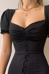 Woman wearing a black sweetheart-neck midi dress with puff sleeves, ruched detailing, and a button-front slit.