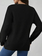 Woman wearing a black tie-front long sleeve knit cardigan with three bow ties paired with blue jeans.