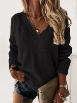 Woman wearing a black V-neck long sleeve knit top with ribbed neckline and cuffs, styled with black denim shorts.