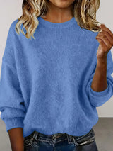 Woman wearing a blue round neck dropped shoulder sweater with dark-wash jeans.