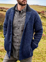 Men's blue chunky knit shawl collar cardigan with button-front closure, ribbed texture, and front pockets, layered over a gray button-down shirt.