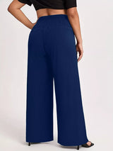 Model wearing blue plus-size high-waisted-leg pants with a smocked waistband and side pockets.