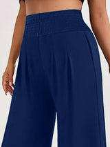 Model wearing blue plus-size high-waisted-leg pants with a smocked waistband and side pockets.