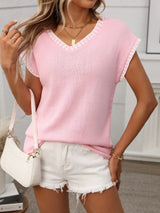 Woman wearing a blushing pink short sleeve knit top with white contrast trim along the V-neckline and sleeves.