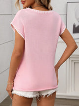 Woman wearing a blushing pink short sleeve knit top with white contrast trim along the V-neckline and sleeves.