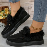 Black loafers with fur trim worn by a person, with a blurred background of flowers and a basket.