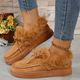 Brown fuzzy loafers worn with jeans on a light wooden floor.