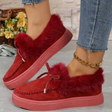 Red slippers with fuzzy trim worn by a person, with a blurred background of flowers and a basket.