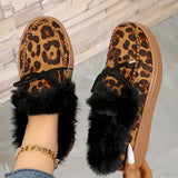 Leopard print slippers with black fur trim worn by a person on a neutral background
