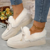 White sneakers with fluffy white laces worn with blue jeans on a light wooden floor.