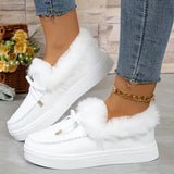 White sneakers with fluffy white laces worn with blue jeans on a light wooden floor.