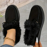 Black fuzzy slippers worn by a person on a neutral background