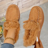 Brown fuzzy slippers with fur trim worn by a person on a light gray surface.