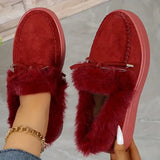 Red slippers with fur trim worn by a person on a neutral background