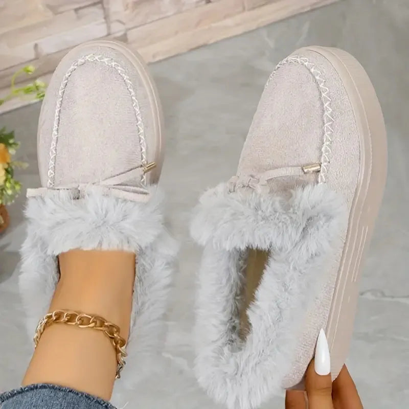 Light gray slippers with fluffy texture worn by a person indoors.
