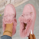 Pink fuzzy slippers worn by a person with a gold chain and white nail polish.