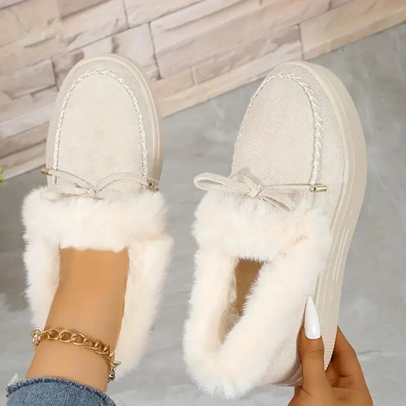 White fuzzy slippers being worn with a neutral background