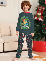 Family wearing matching dark green Hogwarts graphic Christmas pajama tops with coordinating navy holiday print pajama pants.