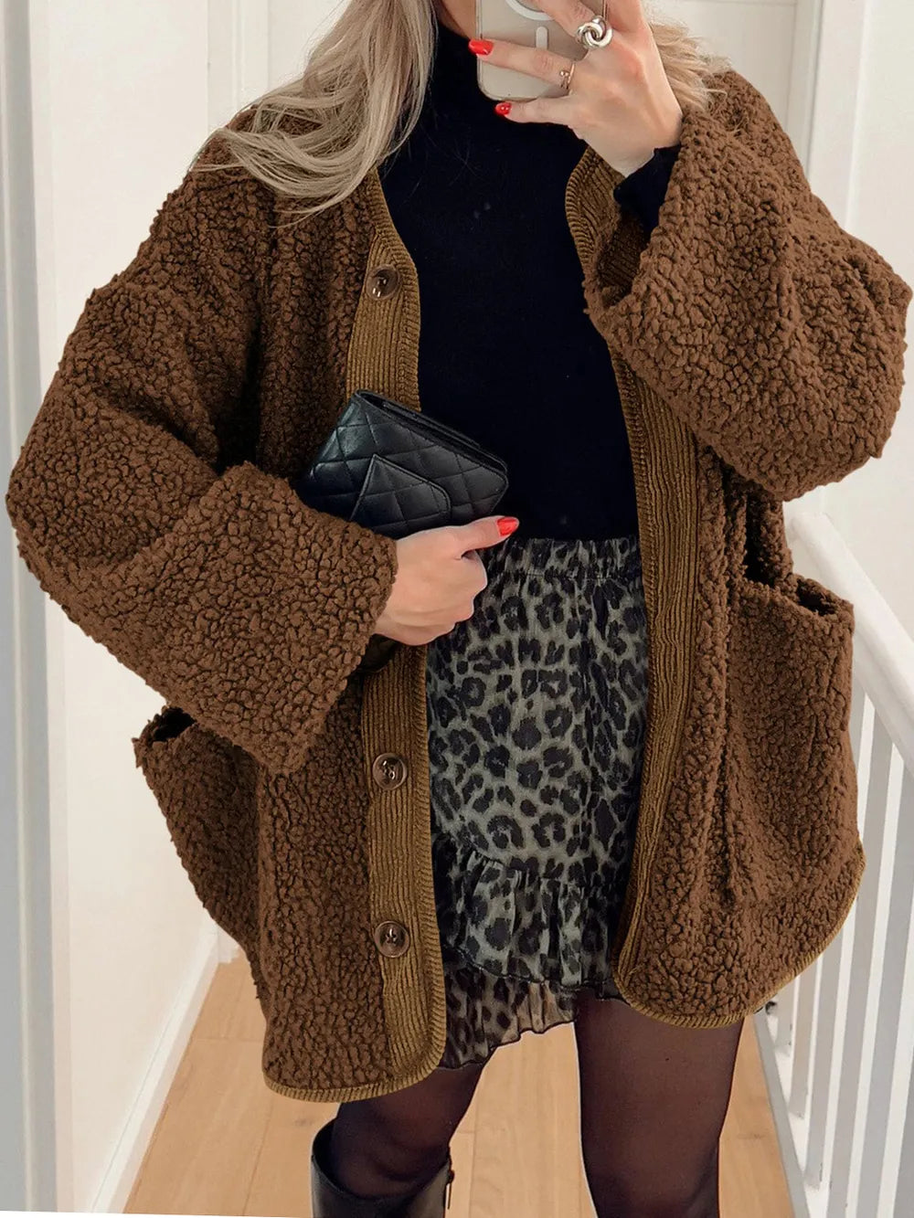 Women's brown textured sherpa jacket with long sleeves and relaxed silhouette, styled over a black hooded outfit.