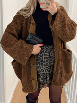 Women's brown textured sherpa jacket with long sleeves and relaxed silhouette, styled over a black hooded outfit.