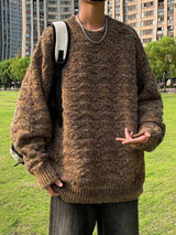 Man wearing an oversized brown textured knit crewneck pullover sweater with long sleeves and ribbed cuffs and hem, styled with dark pants.