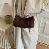 Brown suede vintage-style shoulder bag with a minimalist silhouette paired with a neutral outfit.