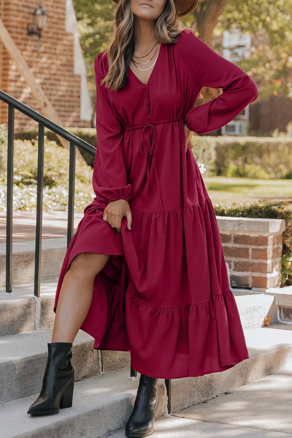 Woman wearing burgundy tiered midi dress with drawstring waist, long sleeves and black ankle boots