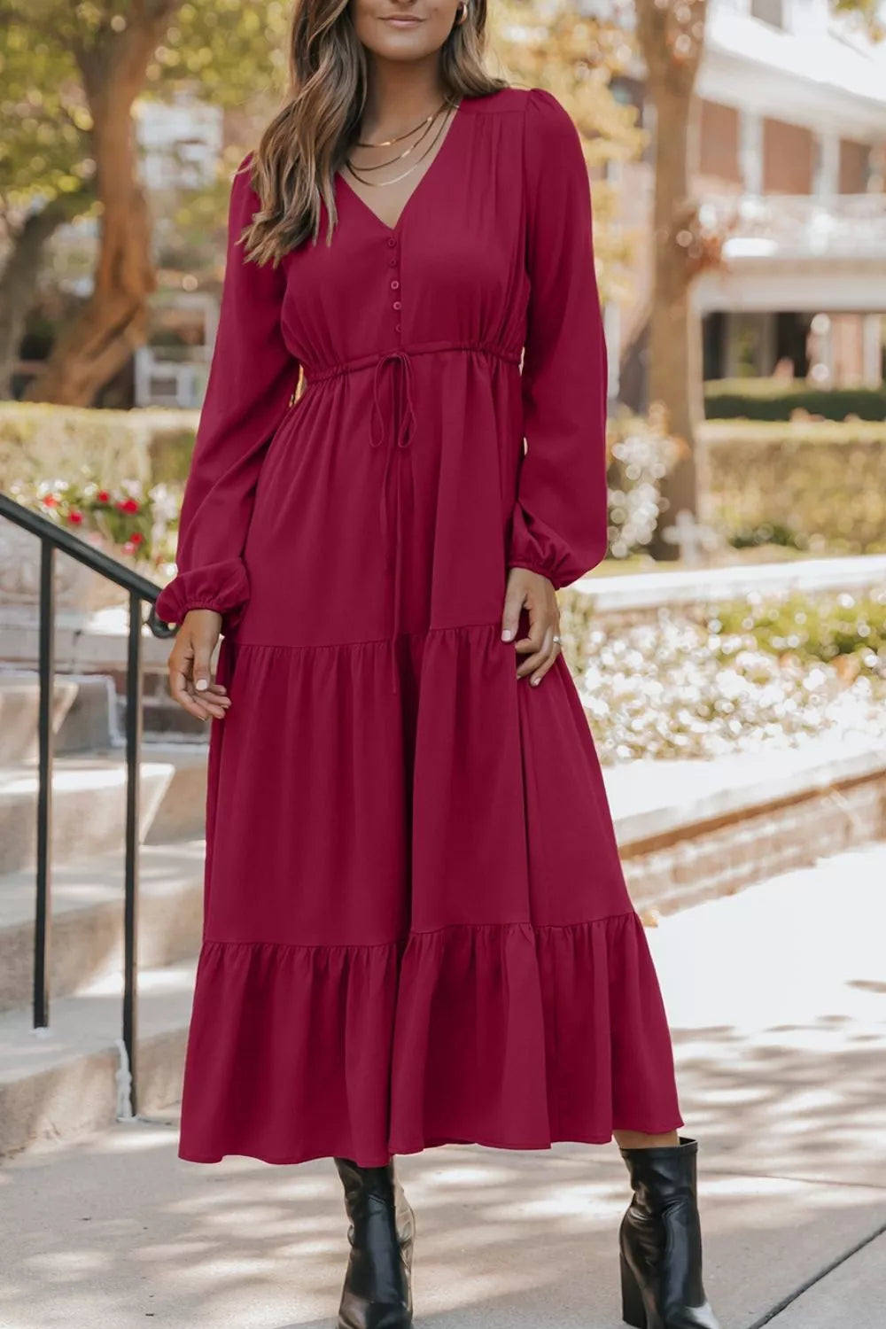 Woman wearing burgundy tiered midi dress with drawstring waist, long sleeves and black ankle boots