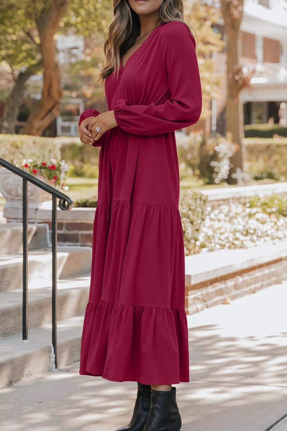 Woman wearing burgundy tiered midi dress with drawstring waist, long sleeves and black ankle boots