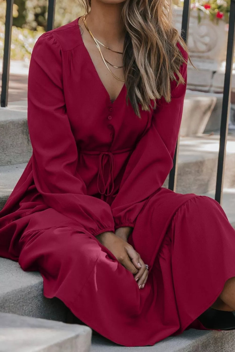 Woman wearing burgundy tiered midi dress with drawstring waist, long sleeves and black ankle boots