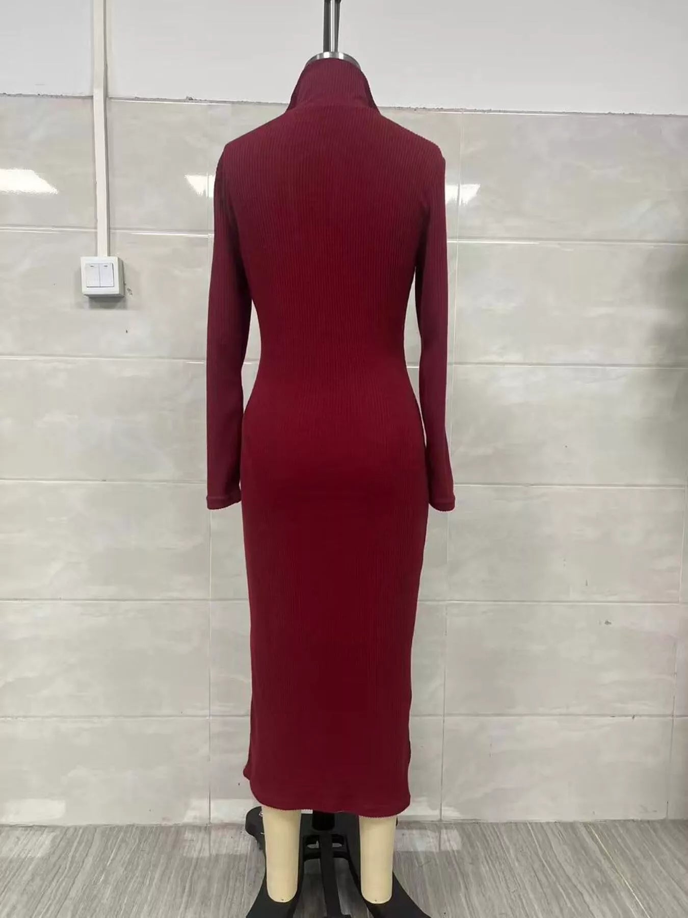 Woman wearing a burgundy ribbed knit V-neck long sleeve sweater dress styled with a black belt and tall brown Western boots.