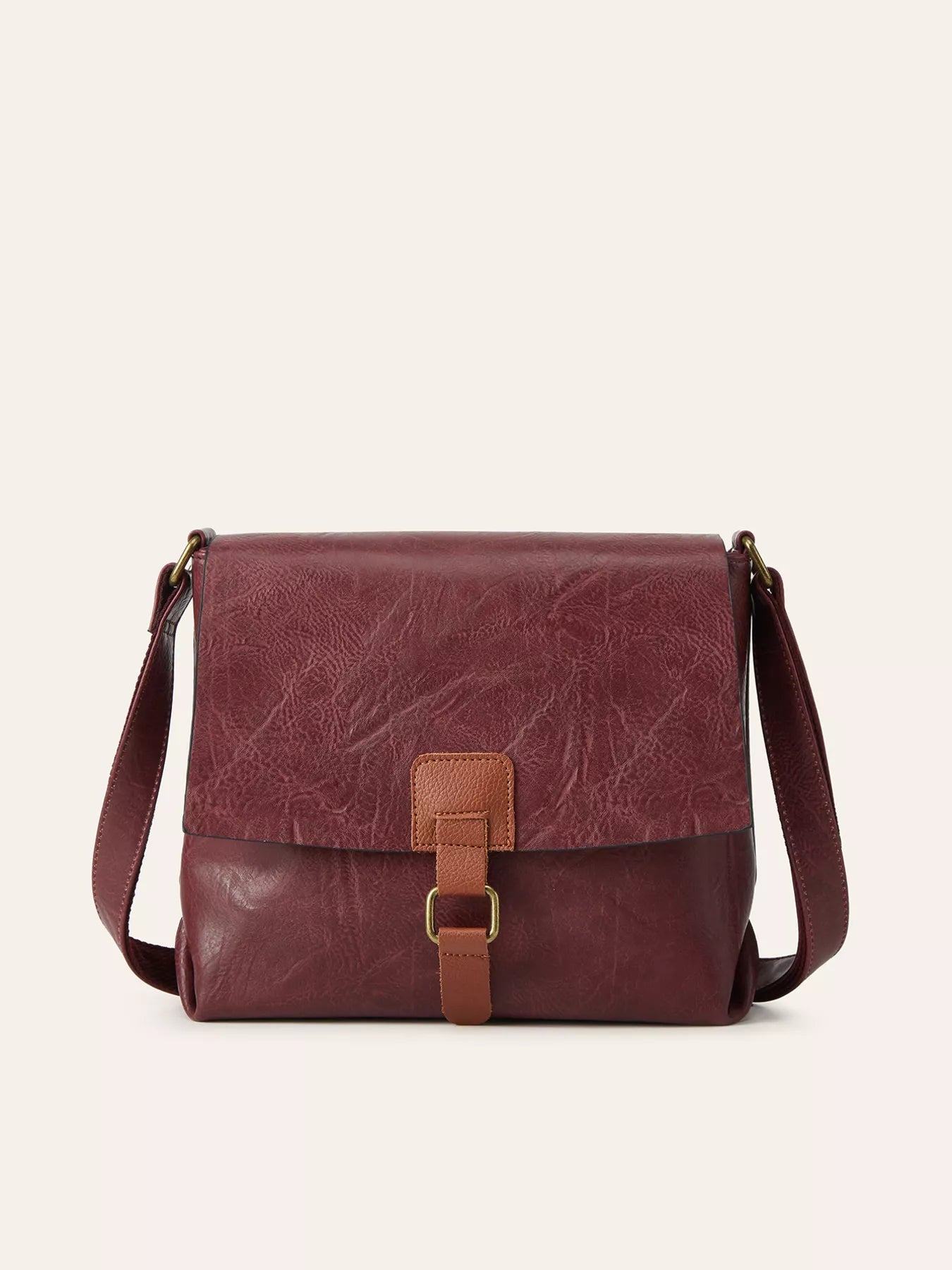 Burgundy vintage-style crossbody bag featuring a flap closure, decorative buckle detail, and adjustable shoulder strap.