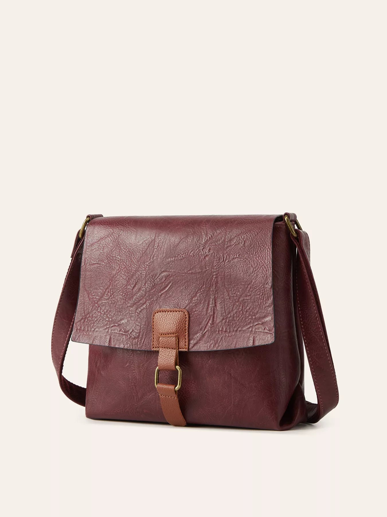 Burgundy vintage-style crossbody bag featuring a flap closure, decorative buckle detail, and adjustable shoulder strap.
