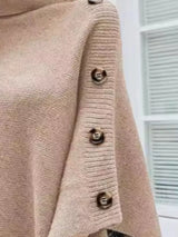Women's apricot turtleneck poncho pullover with decorative sleeve buttons and flowing knit silhouette.