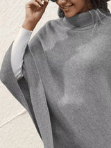 Women's gray turtleneck poncho pullover with decorative sleeve buttons and relaxed knit silhouette.