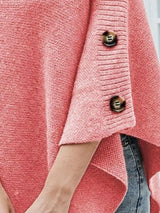 Women's pink knit turtleneck poncho pullover with button accents and flowing poncho silhouette.