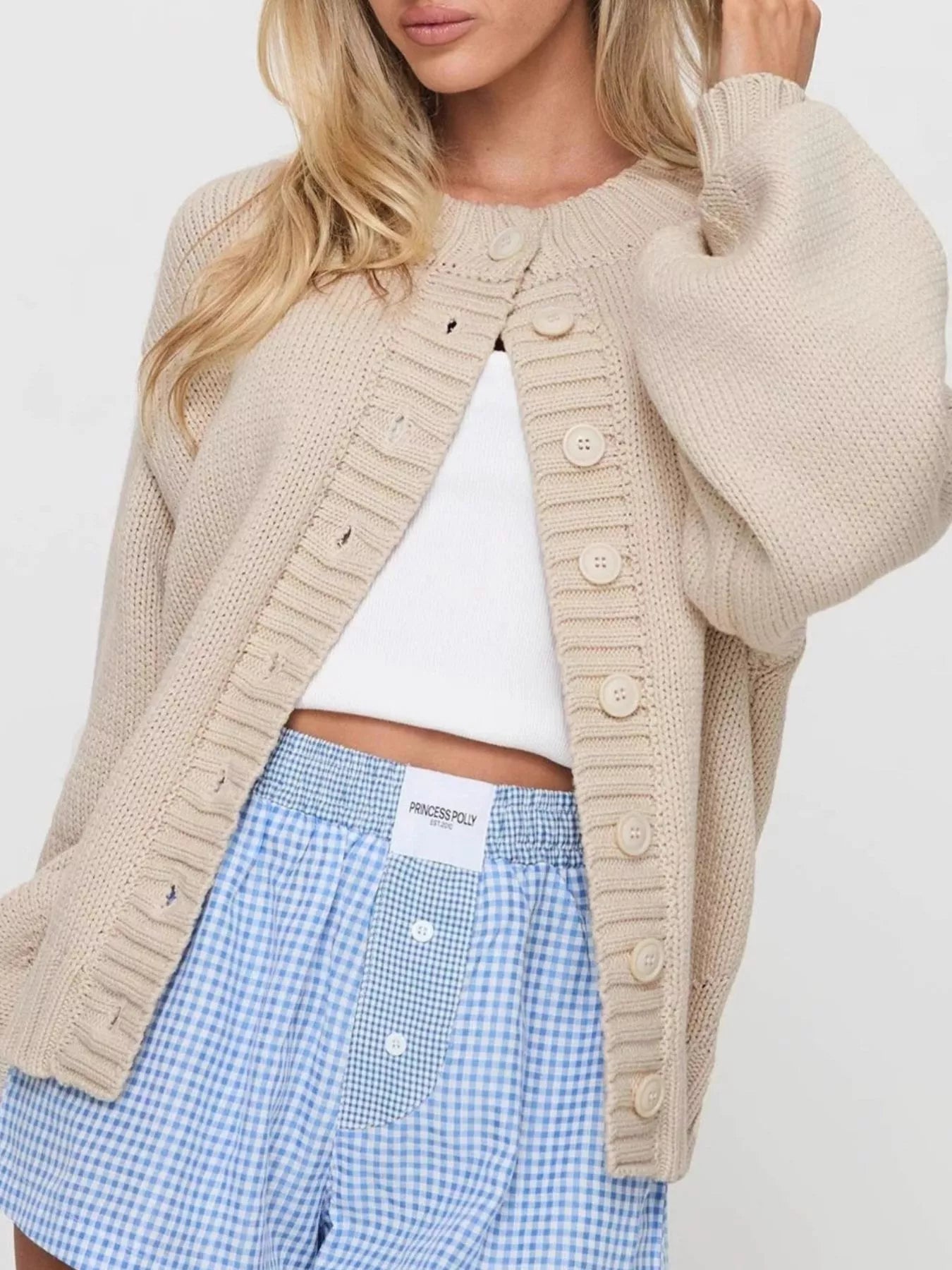 Women's beige button-down knit cardigan featuring a ribbed crew neckline, long sleeves, and relaxed fit. Cozy boutique sweater perfect for layering with jeans, dresses, or casual fall outfits.