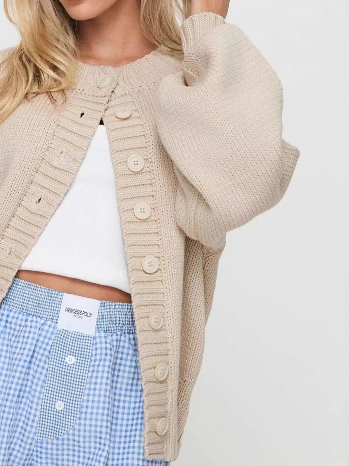 Women's beige button-down knit cardigan featuring a ribbed crew neckline, long sleeves, and relaxed fit. Cozy boutique sweater perfect for layering with jeans, dresses, or casual fall outfits.