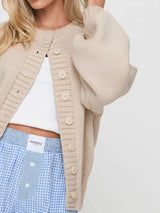Women's beige button-down knit cardigan featuring a ribbed crew neckline, long sleeves, and relaxed fit. Cozy boutique sweater perfect for layering with jeans, dresses, or casual fall outfits.