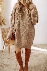 Woman wearing a tan cable knit long sleeve sweater dress styled with knee-high brown boots and layered gold necklaces.