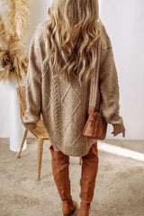 Woman wearing a tan cable knit long sleeve sweater dress styled with knee-high brown boots and layered gold necklaces.