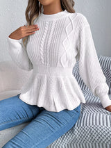 Woman wearing a white cable knit round neck peplum sweater with long sleeves and blue jeans.