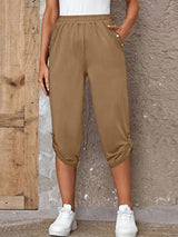Model wearing camel roll-tab capri pants with side pockets and white sneakers for a casual outdoor look.